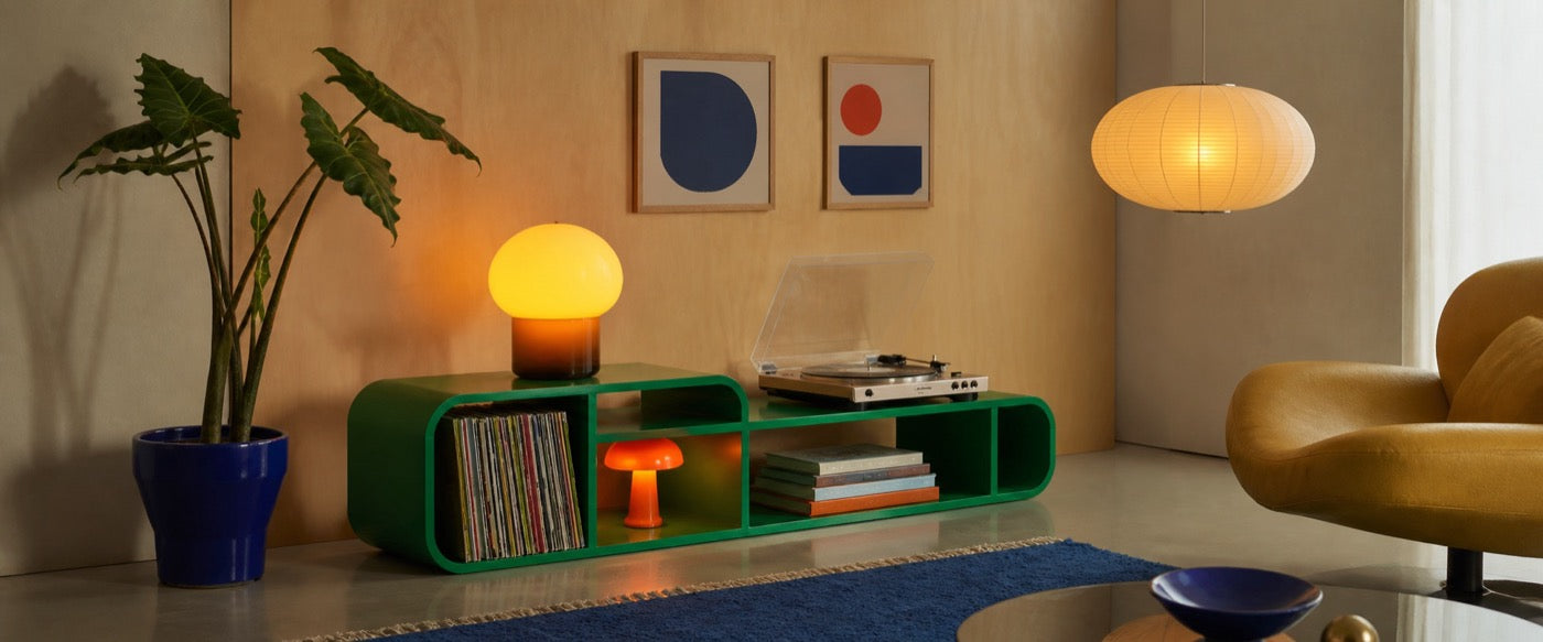 A living room with a green sideboard, paper lantern and warm table lamp